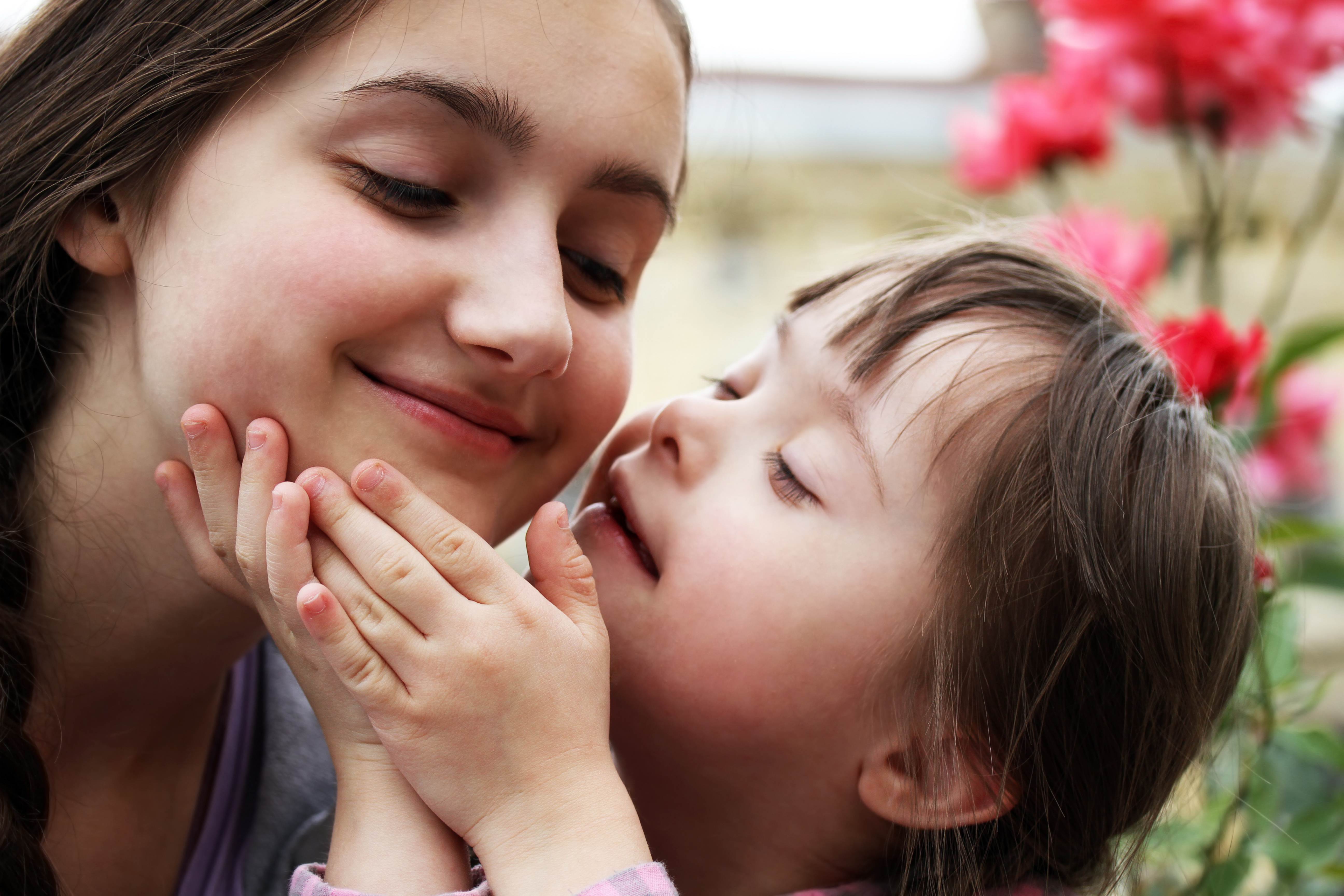: Image of a smiling young girl with Down syndrome touching the face of another girl