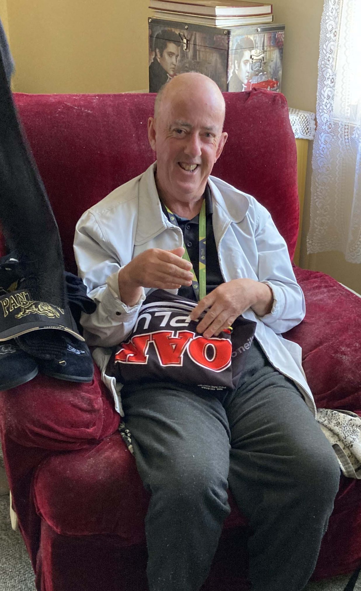 Brett sitting on red armchair and smiling at the camera.