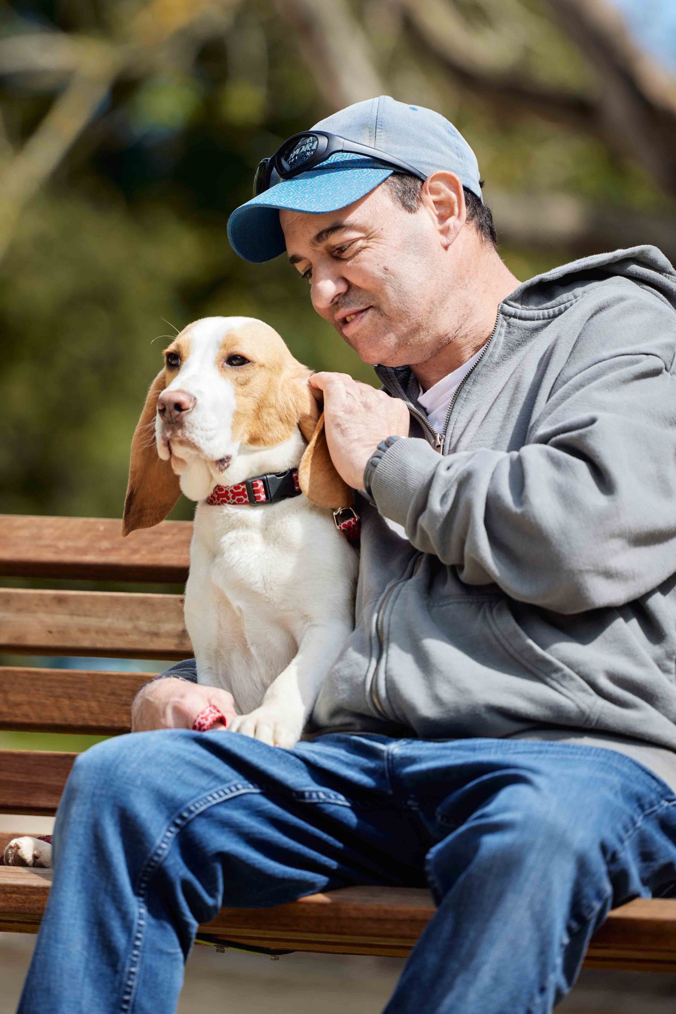 Client sitting on park bench and patting a dog.