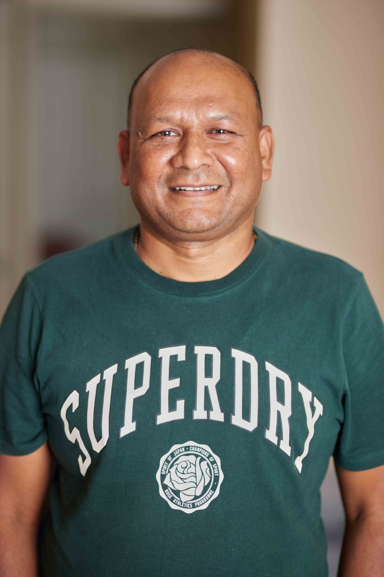 A man in a green t-shirt smiling at the camera.