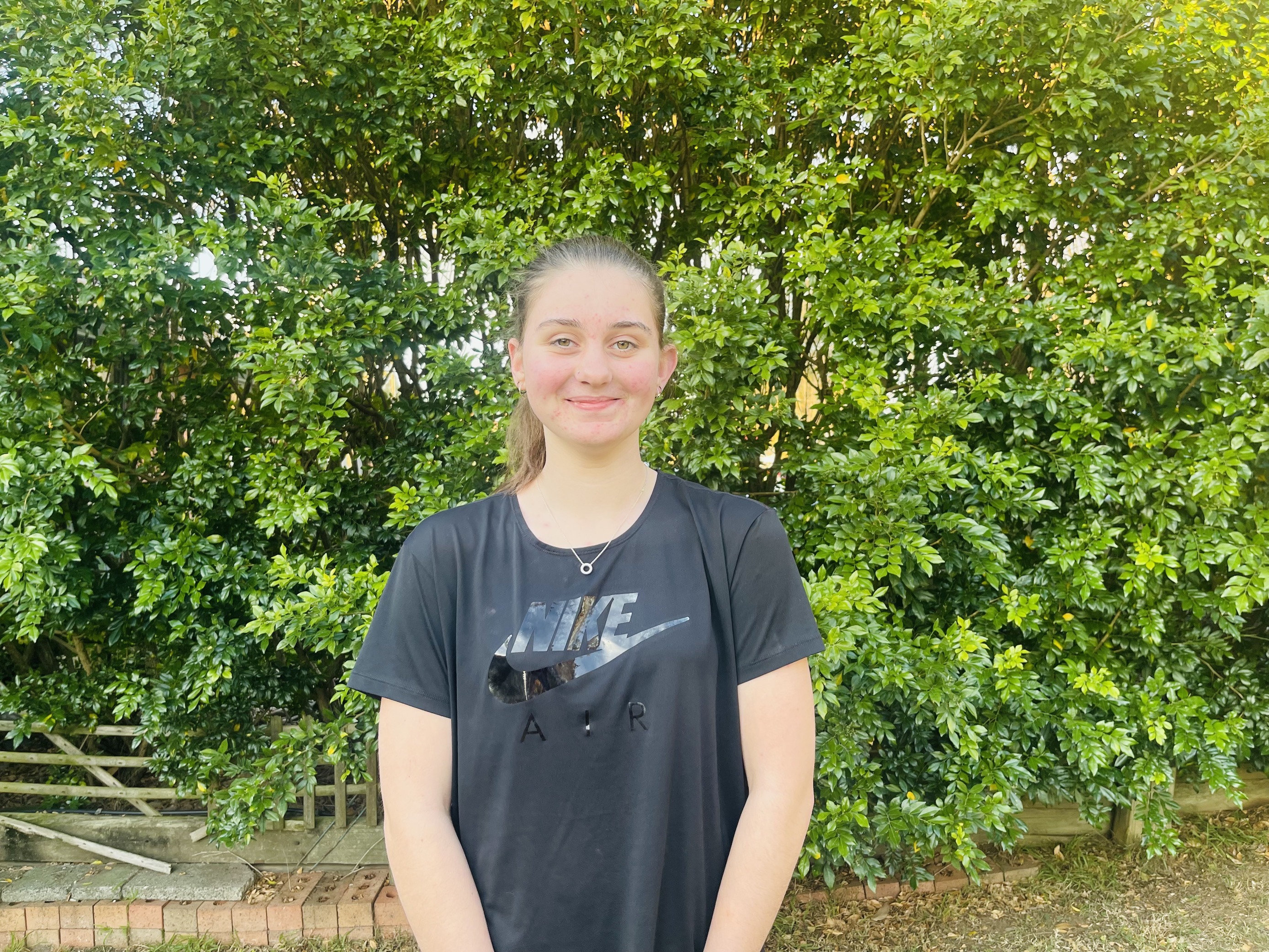 Girl in a black t-shirt smiling at the camera.