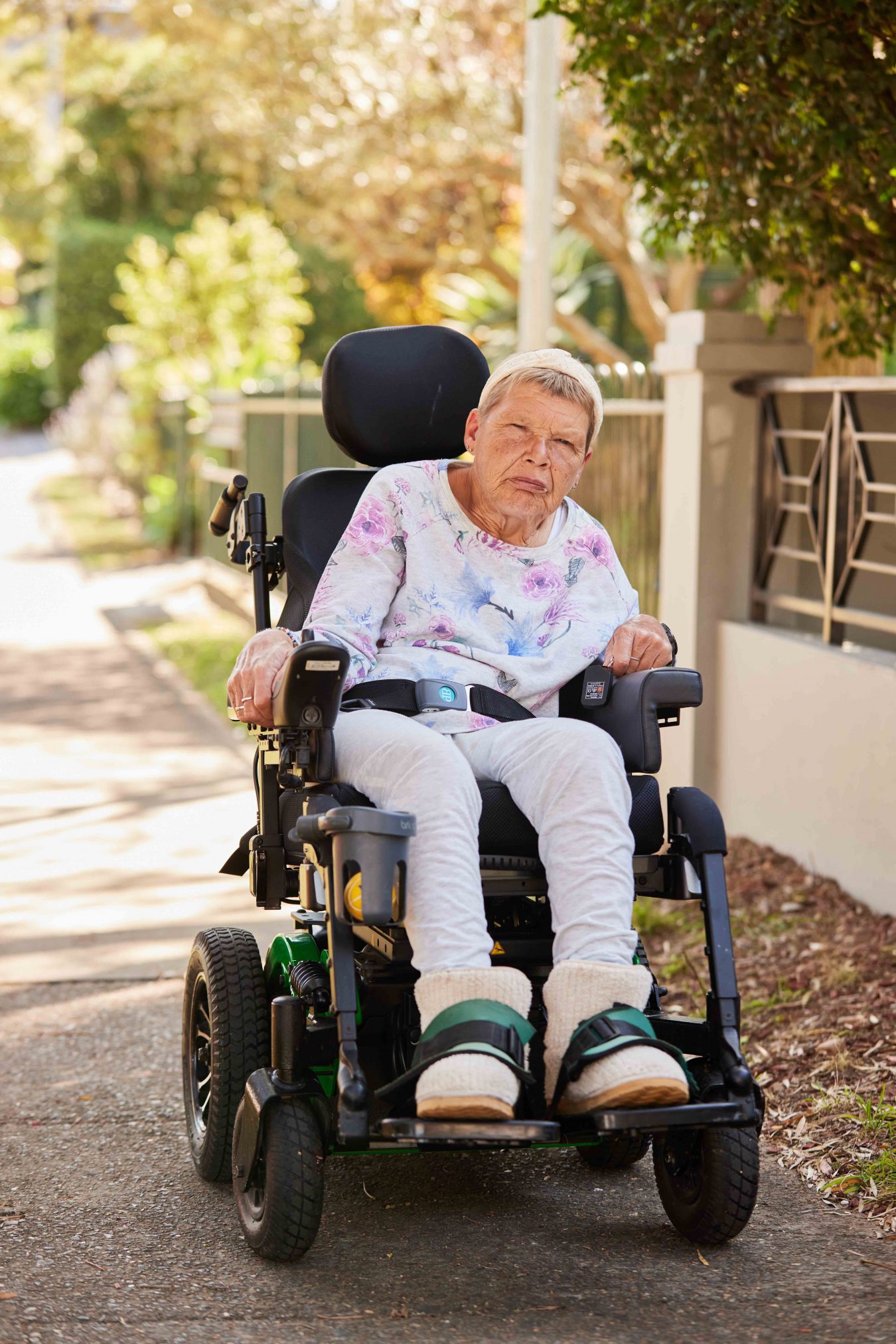 Woman in a powerchair on a footpath, looking stern